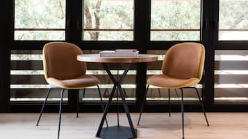 Kaksi ruskeaa tuolia, joissa on keltaisia yksityiskohtia, on sijoitettu pyöreän puupöydän ympärille. Pöydällä on kirja, jonka nimi on ”The Design Hotels”.