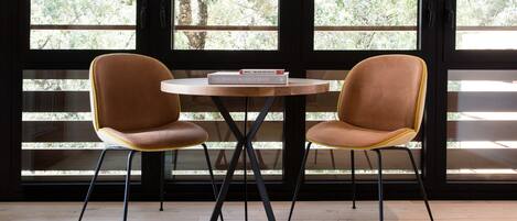 Two brown chairs with yellow accents around a round wooden table with a book titled "The Design Hotels" on it.