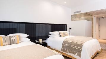 A modern hotel room with two beds, a large mirror, and a wooden floor.