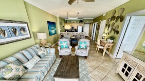 A living room with a striped sofa, two armchairs, a coffee table, and a dining area with a wooden table and chairs. - Highly Rated, 2 Bed/2 Bath Ocean Reef Condo, Fabulous Reviews, Beach Service (Panama City Beach)