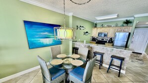 A dining area with a glass table, wicker chairs, and a hanging light fixture. - Highly Rated, 2 Bed/2 Bath Ocean Reef Condo, Fabulous Reviews, Beach Service (Panama City Beach)
