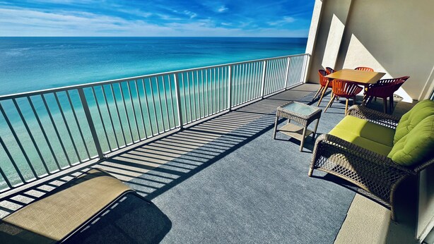 A balcony with a view of the ocean, a table with chairs, and a sofa with cushions. - Highly Rated, 2 Bed/2 Bath Ocean Reef Condo, Fabulous Reviews, Beach Service (Panama City Beach)