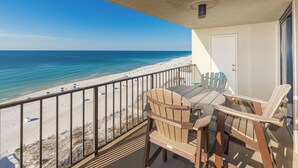 Un balcon donnant sur une plage, avec une table et deux chaises.