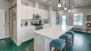A modern kitchen with white cabinetry, stainless steel appliances, and a large island with bar stools.