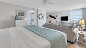 Une chambre à coucher comprenant un lit, une commode, un téléviseur, un canapé et une lampe.