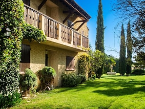 A two-story building with a balcony, surrounded by greenery and a well-maintained lawn. - Homerez - Provencal Villa with Pool in Barbentane (Barbentane)