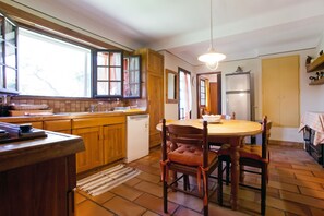 A kitchen with wooden cabinets, a dishwasher, a dining table with chairs, and a hanging light fixture. - Homerez - Provencal Villa with Pool in Barbentane (Barbentane)