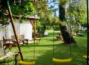 A garden with a swing set, wooden chairs, and a small shed. - Homerez - Provencal Villa with Pool in Barbentane (Barbentane)