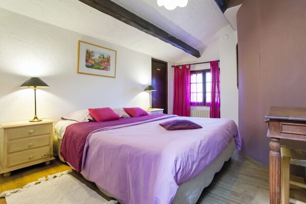 A bedroom with a bed, two bedside tables, a nightstand, a window with curtains, and a painting on the wall. - Homerez - Provencal Villa with Pool in Barbentane (Barbentane)