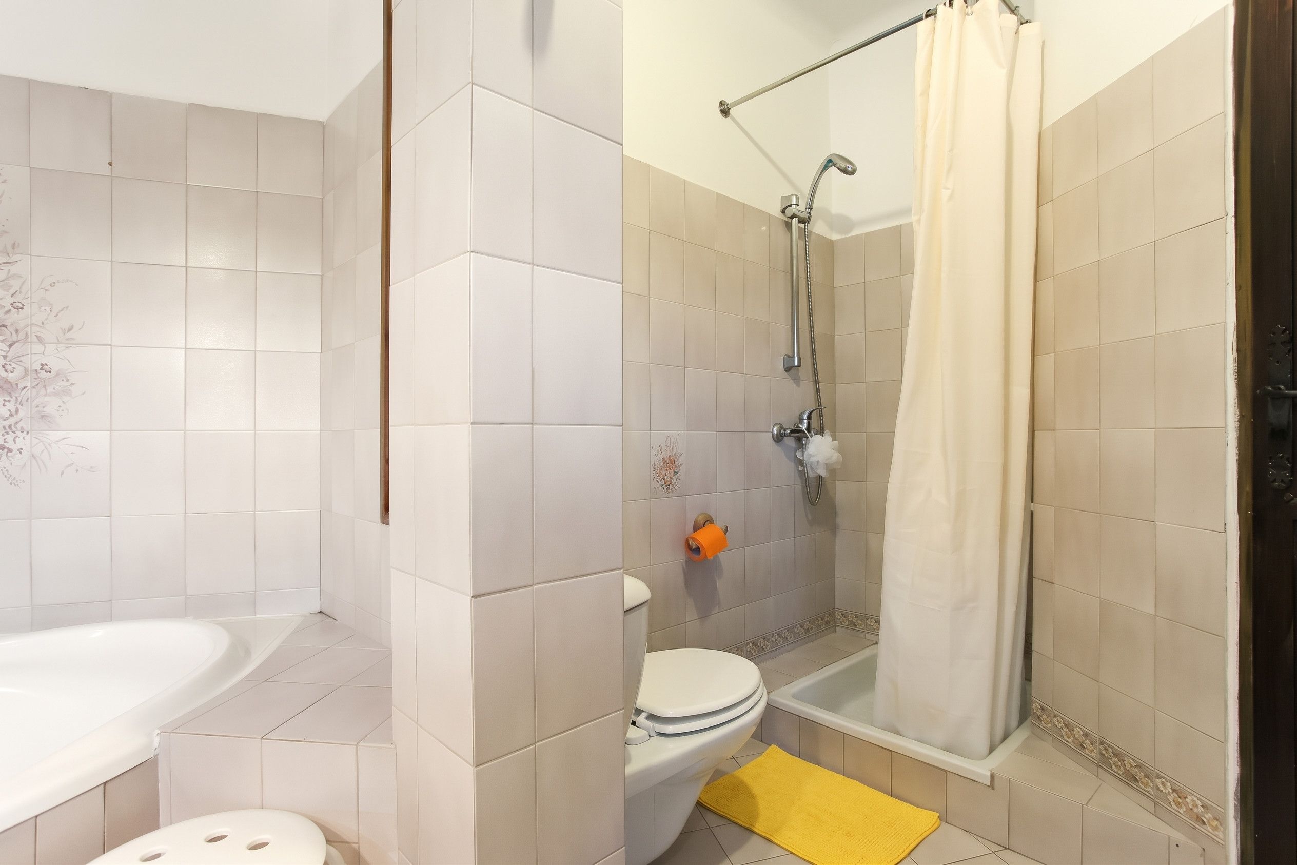 A bathroom with a bathtub, toilet, and shower area.