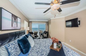 Une chambre d’hôtel comprenant un lit, un ventilateur de plafond, une télévision, un balcon avec vue et un coin repas.
