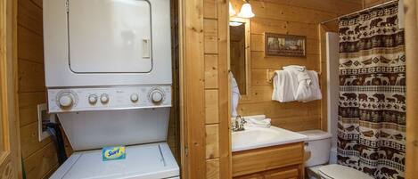 Une petite salle de bain équipée d’un lave-linge, d’un évier et de toilettes.