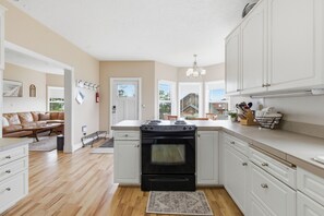 A kitchen with white cabinets, a black stove, and a wooden floor.