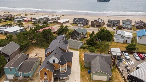 Een woongebied aan de kust met huizen, een strand en een rotsachtige landtong in de verte.