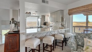 A modern kitchen with a bar area, white cabinetry, and a view of the outdoors.