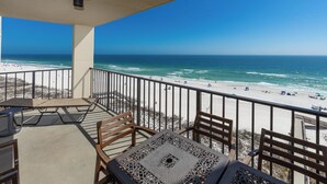 Ein Balkon mit Blick auf einen Strand, einem Tisch und Stühlen.