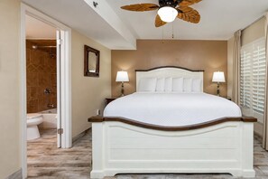 A bedroom with a bed, bedside lamps, a ceiling fan, and a view of the bathroom. - One Bedroom…7th Floor of Phoenix II…Gulf Front Balcony (Orange Beach)