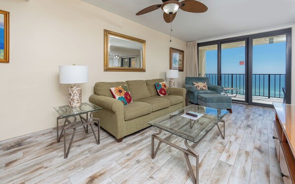 A living room with a sofa, armchairs, a coffee table, and a balcony with a view. - One Bedroom…7th Floor of Phoenix II…Gulf Front Balcony (Orange Beach)