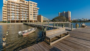 Een hotel aan het water met een aanlegsteiger, een boot en een modern gebouw met balkons.