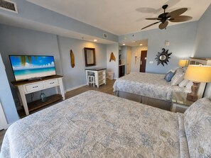 A bedroom with two beds, a TV, a desk, and a ceiling fan. - Remodeled. Luau 6705 in Sandestin.Tram, wifi, larger Studio with balcony (Miramar Beach)