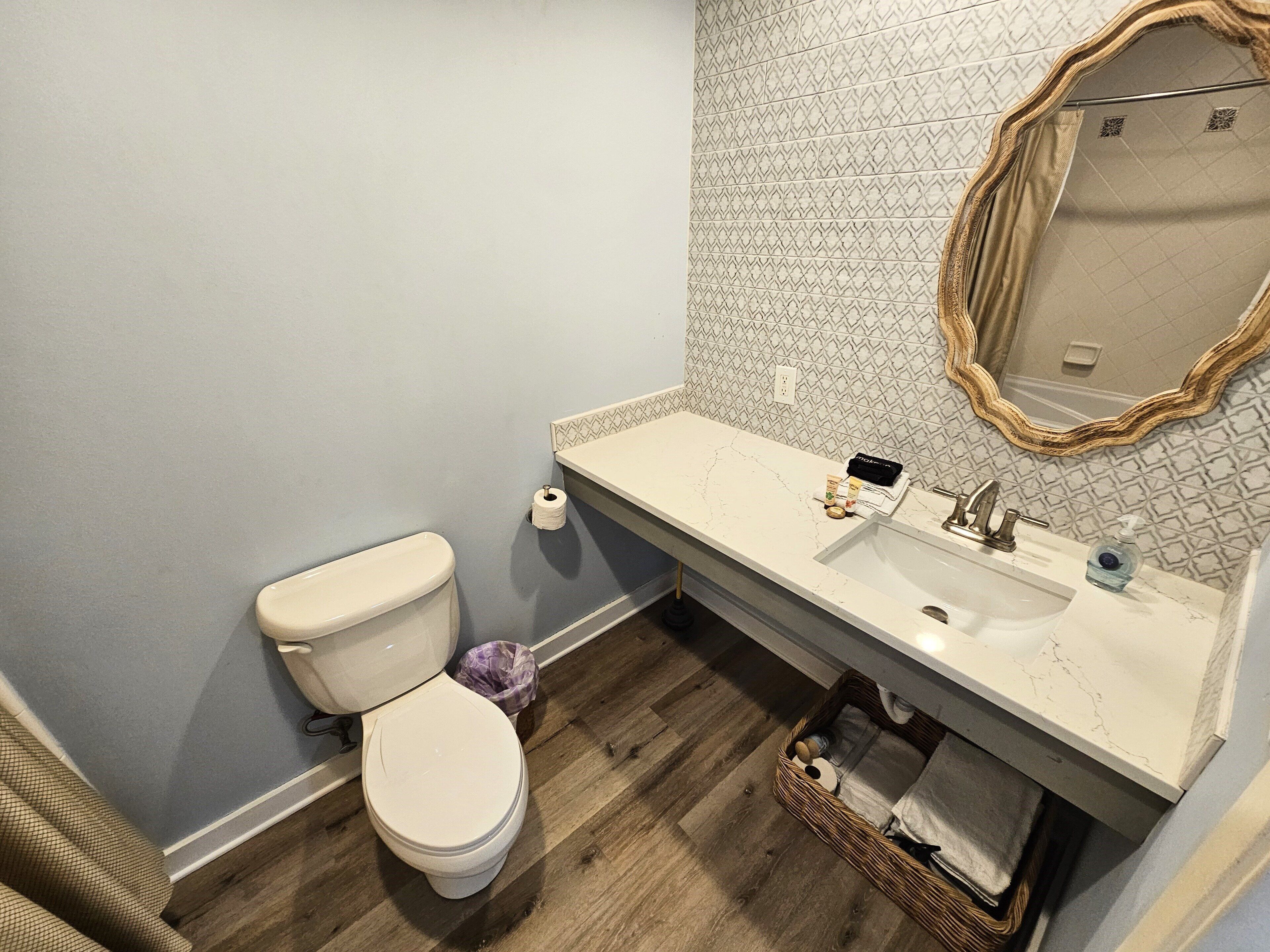 A bathroom with a toilet, sink, and mirror.