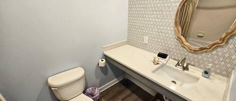A bathroom with a toilet, sink, and mirror.