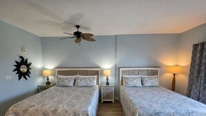 A hotel room with two beds, a ceiling fan, bedside lamps, and a sun-shaped wall decoration. - Remodeled.  Luau 6705 in Sandestin.Tram, wifi, larger Studio with balcony (Miramar Beach)