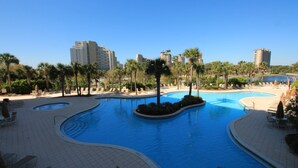 A swimming pool with a curved design, surrounded by palm trees and lounge chairs. - Remodeled.  Luau 6705 in Sandestin.Tram, wifi, larger Studio with balcony (Miramar Beach)