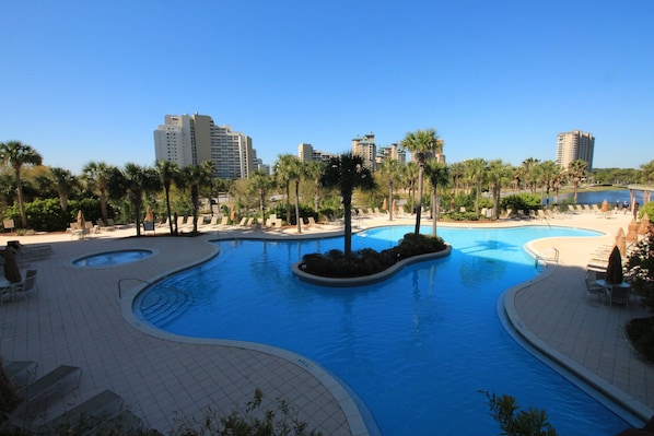 A swimming pool with a curved design, surrounded by palm trees and lounge chairs. - Remodeled. Luau 6705 in Sandestin.Tram, wifi, larger Studio with balcony (Miramar Beach)