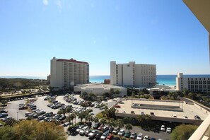 A hotel complex with multiple buildings, a parking lot, and a view of the beach.