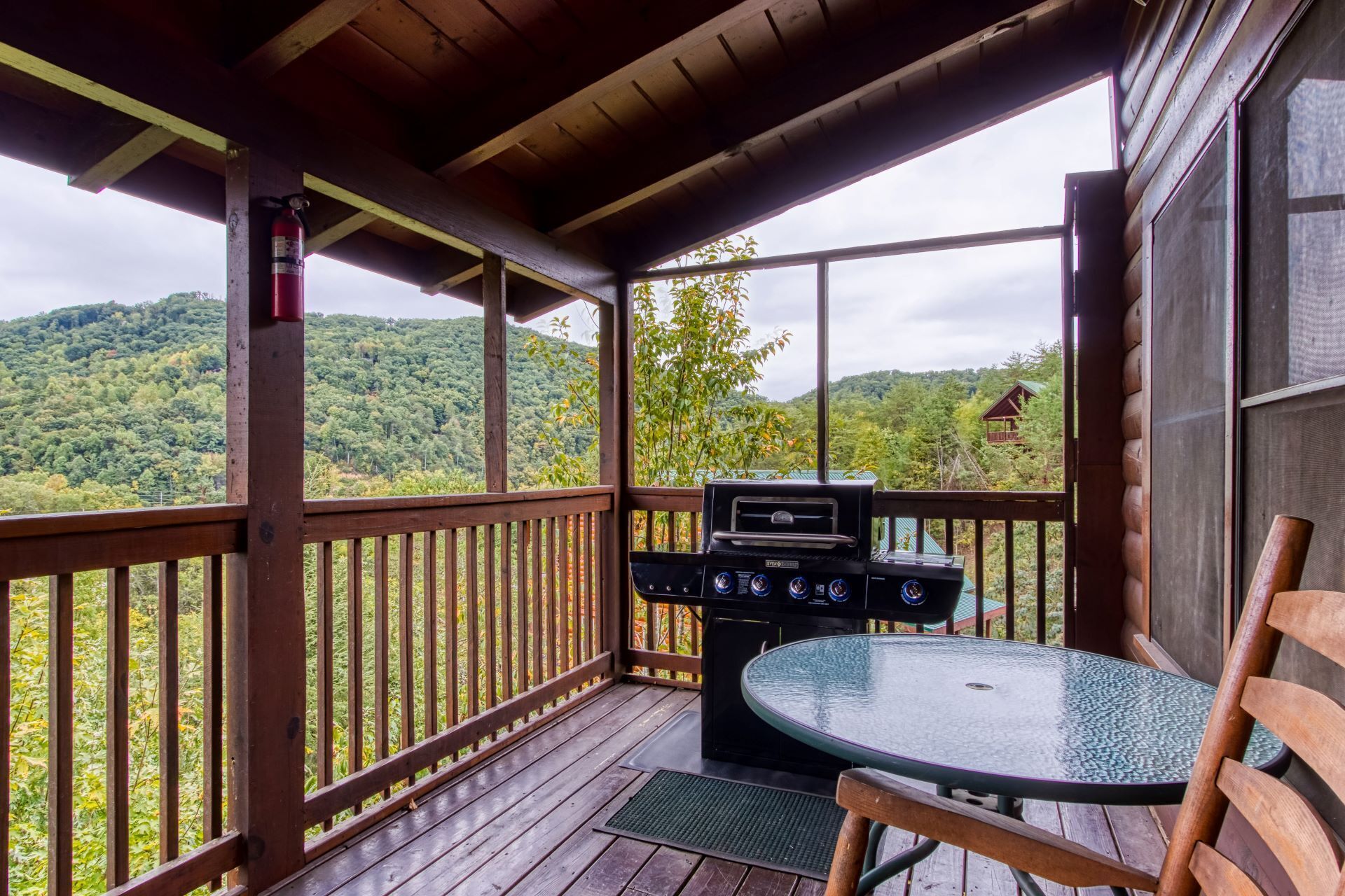 A covered outdoor area with a grill, a table, and a chair.