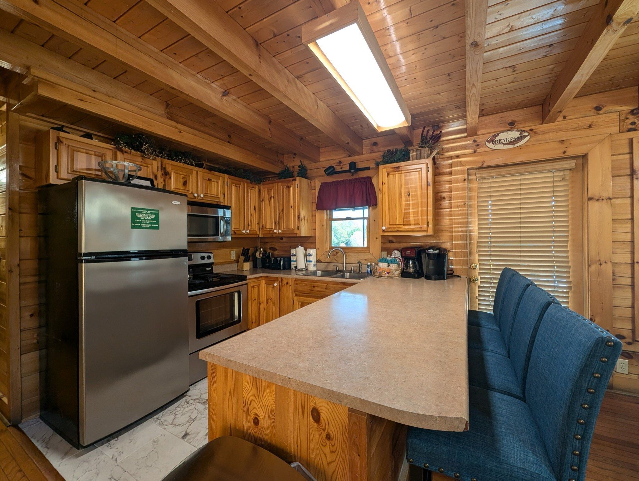 A wooden cabin kitchen with a refrigerator, stove, microwave, and wooden cabinets.