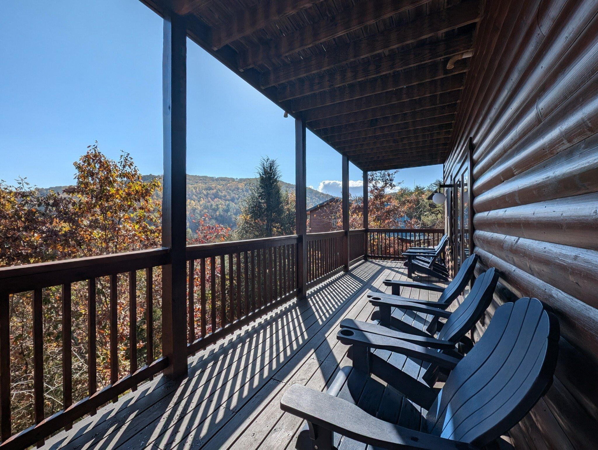 A wooden deck with a view of autumn foliage and mountains.