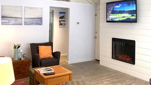 Una sala de estar moderna con chimenea, un televisor montado en la pared y un letrero que dice "BEACH".