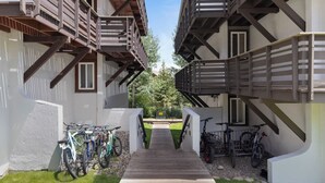 A narrow pathway leading to a building with wooden balconies and bicycles parked along the sides. - Outpost: Tensleep B1 - Hot Tub Access (Teton Village)