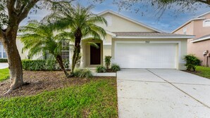 A single-story house with a garage, a palm tree, and a well-maintained lawn. - Budget Friendly! Lake View Home with a Private pool nearby to Disney (Davenport)