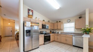 A modern kitchen with stainless steel appliances, wooden cabinets, and a tiled floor. - Budget Friendly! Lake View Home with a Private pool nearby to Disney (Davenport)