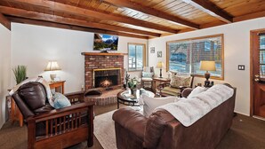 A cozy living room with a fireplace, leather furniture, and large windows.