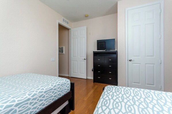 Un dormitorio con dos camas, un aparador, un televisor y una puerta.