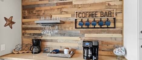 A kitchen with a wooden wall, coffee bar sign, coffee machines, and a starfish decoration.