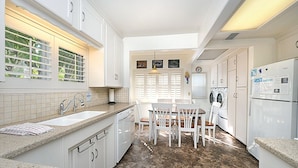A kitchen with white cabinets, a granite countertop, a dining table with chairs, a washing machine, and a refrigerator. - 359CA: Charming Family Home, 3 Blocks to Beach, Restaurants and Shops (Avalon)