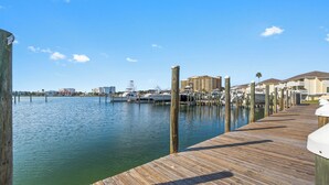 A wooden pier extending into calm waters with boats docked nearby and buildings in the background. - Cozy Beachwalk 2BR | Short Walk to the Beach (Destin)