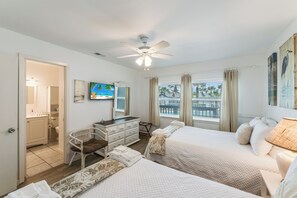 A hotel room with two beds, a ceiling fan, a desk, a chair, and a window with curtains. - Beachfront! Costal breezes and beachviews in the heart of Port Aransas!  Communi (Port Aransas)