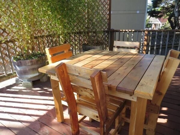 A wooden deck with a table and chairs, surrounded by a lattice fence and a potted plant. - Sea Star Spa – Hot Tub, Walk to Beach (Florence)