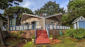 A two-story house with a red carpet leading to the front door, surrounded by a wooden fence and a small garden.