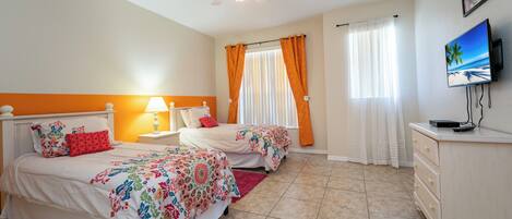 A bedroom with two beds, a ceiling fan, a TV, and a dresser.