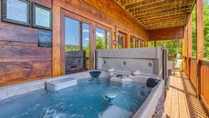 Un ponte in legno con vasca idromassaggio e una struttura in legno tipo baita.