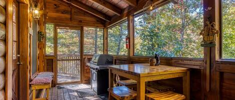 Une cabane en bois avec une terrasse, un barbecue et un banc.