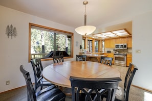 Une cuisine moderne avec des meubles en bois, une table à manger avec des chaises et une grande fenêtre.