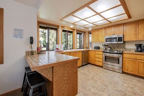 Une cuisine moderne avec des meubles en bois, un four en acier inoxydable et un grand îlot central doté de tabourets.